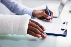 Injured man signing a personal injury form in Pascagoula with the help of an attorney.